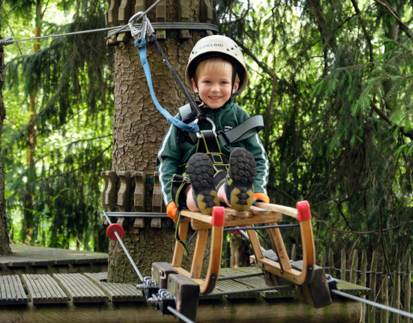 Anfahrt zum TreeRock Junge sitzt auf einem Schlitten der Seilbahn